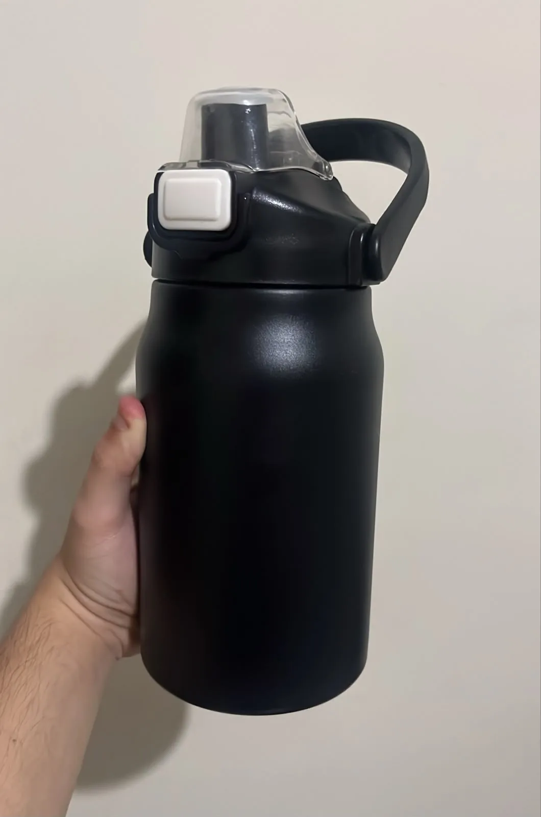 Foto de celular de uma garrafa térmica preta na mão